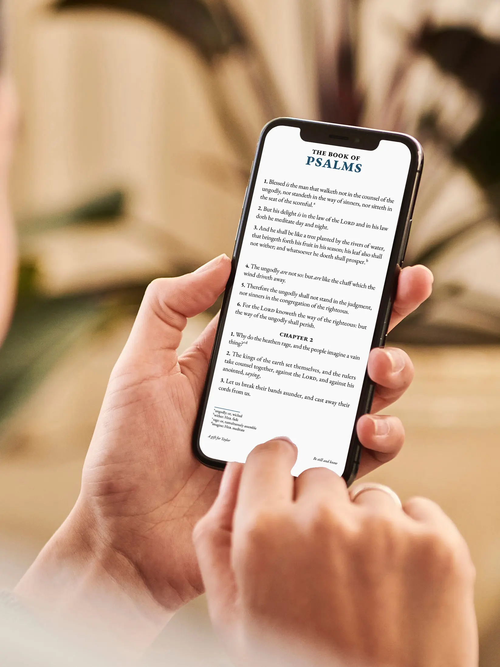 Person reading Personal Edition on smartphone, showing Book of Psalms with blue accents and custom footer